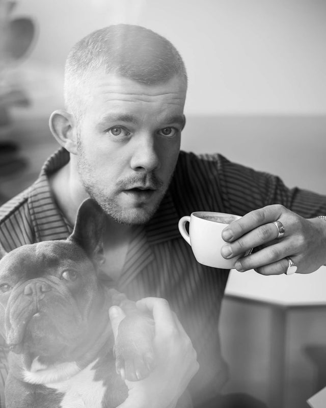 Russel Tovy wearing a Stephen Einhorn signet ring, holding a cup and a dog
